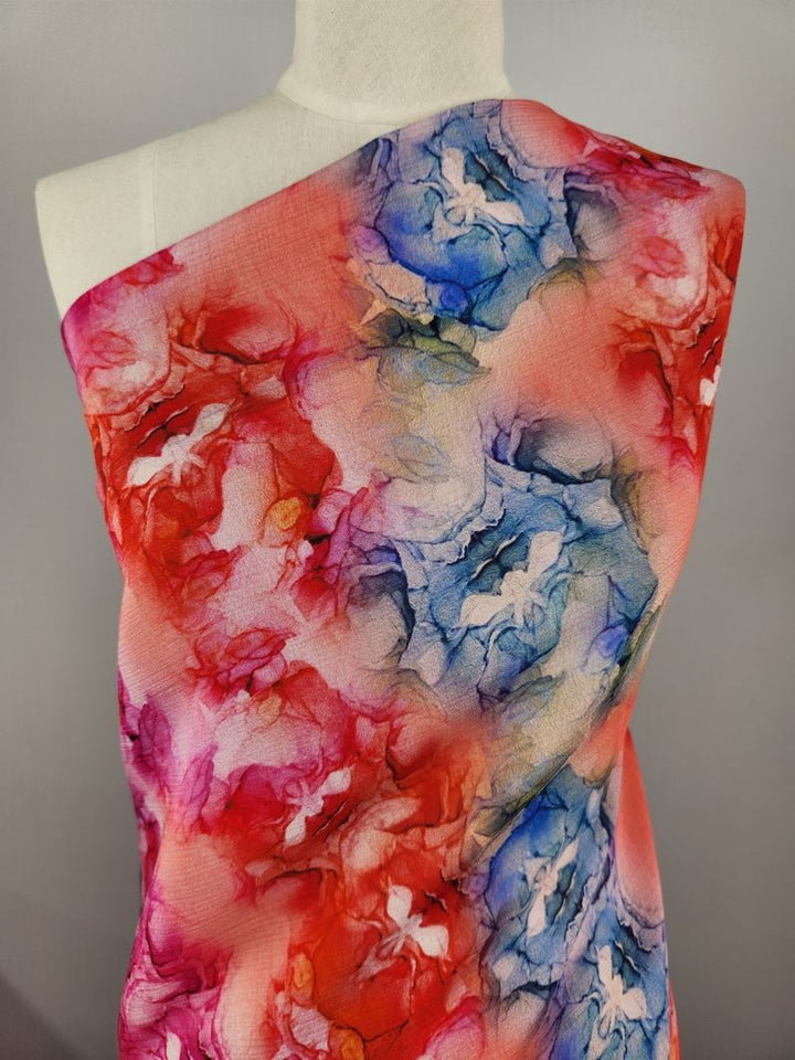 A mannequin adorned with Designer Cotton - Roses from Super Cheap Fabrics showcases an abstract floral design interwoven with geometric prints. The vivid combination of reds, blues, and pinks offers a dynamic and artistic pattern ideal for luxury sewing projects.