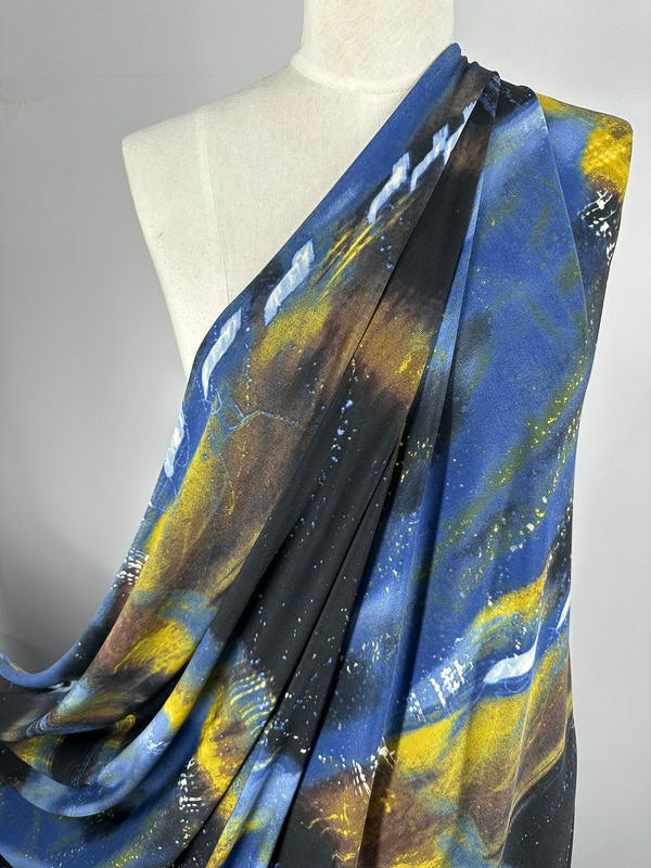 Image of a mannequin draped in medium-weight Printed Lycra - Astro from Super Cheap Fabrics, featuring a blue, yellow, black, and white abstract pattern. The 150cm fabric appears soft and light, with multiple colors blending seamlessly to create a vibrant and dynamic design.