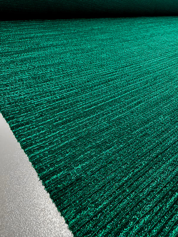 A close-up, oblique view of a textured green surface with a horizontal pattern extending out of the frame into the distance. The appearance is plush and soft, reminiscent of medium to heavy weight knit fabric used in dresses, much like Super Cheap Fabrics' Metallic Knit - Amazon - 150cm, with varying shades of green creating a rich and dynamic look.