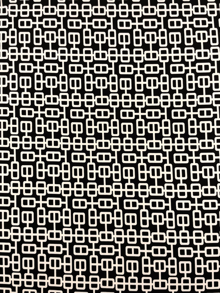 A medium weight polyester fabric with a black background and a repeating cream geometric pattern of interlocking rectangles and squares forming a continuous, grid-like design is known as the Printed Lycra - Link - 150cm by Super Cheap Fabrics.