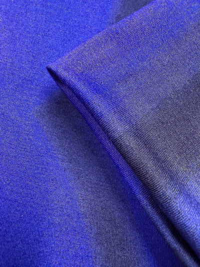 A close-up of Super Cheap Fabrics' Viscose Knit - Ocean Blur (140cm) showcases its smooth texture, gentle sheen, and soft drape in deep blue and purple shades, emphasizing the breathable quality under light.