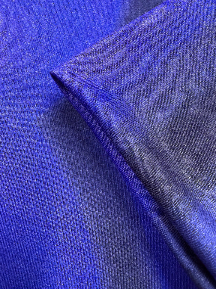 A close-up of Super Cheap Fabrics' Viscose Knit - Ocean Blur (140cm) showcases its smooth texture, gentle sheen, and soft drape in deep blue and purple shades, emphasizing the breathable quality under light.