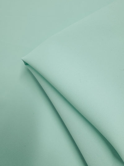 A close-up of folded Microfibre Suiting - Bay - 150cm by Super Cheap Fabrics in mint green, featuring smooth texture, clean edges, and soft even color—quality polyester ideal for elegant garments.