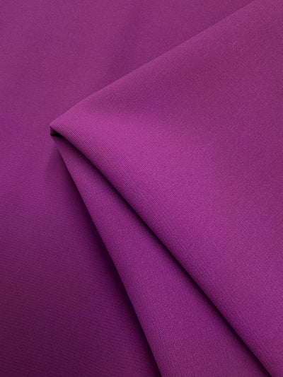 A close-up of Microfibre Suiting - Purple Wine - 150cm by Super Cheap Fabrics shows its smooth, matte polyester finish and fine texture—ideal for lightweight fabric projects.