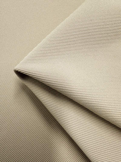 Close-up image of Super Cheap Fabrics' Stretch Twill - Putty - 135cm, showcasing its light beige fabric with a textured, ribbed pattern. The soft-to-the-touch material is neatly folded to highlight the detailed weave and texture.