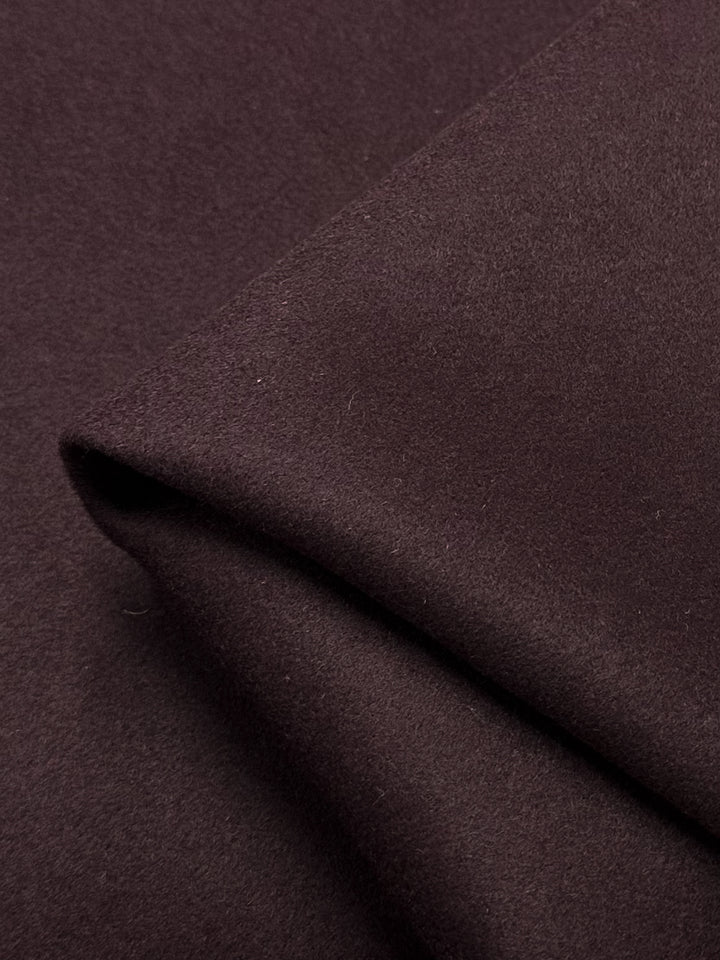 A close-up image of the Melton Wool - Red Mahogany - 152cm fabric by Super Cheap Fabrics, showcasing its heavy weight and soft texture. The folded fabric creates subtle shadows and slight variations in color due to the lighting. Ideal for skirts, jackets, and coats.