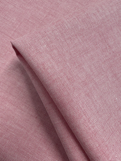 A close-up of Super Cheap Fabrics' Oxford Cotton - Confetti - 146cm shows folded pink and white fabric with a fine grid weave and soft cotton texture.