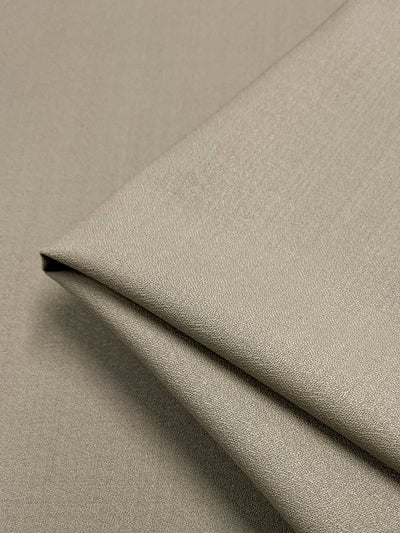 A close-up image of a neatly folded piece of the Merino Wool Suiting in Oxford Tan, featuring a smooth texture. The fabric's fine weave and soft sheen, indicative of luxurious texture, reveal its high-quality material from Super Cheap Fabrics. Additionally, the excellent breathability and perfectly aligned edges showcase a clean and precise fold.