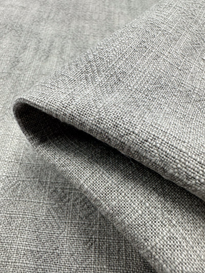 Close-up of a folded piece of Super Cheap Fabrics' Basket Dyed Cotton in silver grey, featuring a subtle twill weave pattern that highlights the intricate detail and quality of the 140cm wide material.