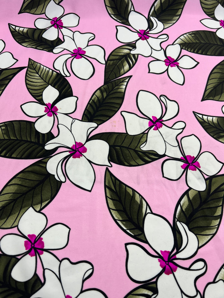 The Printed Nylon Lycra - Paraplu by Super Cheap Fabrics features a vibrant pink background adorned with large white flowers, detailed with green leaves, darker green veins, and magenta centers. The high-quality print ensures an evenly distributed design for a lively appearance. This light to medium weight fabric, measuring 145cm in width, is perfect for multi-use projects. 
