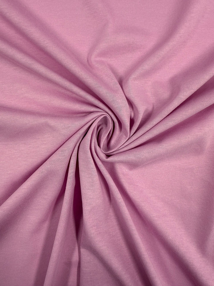 Super Cheap Fabrics’ Cotton Jersey - Pink Lavender - 155cm features a soft, lightweight texture with gentle folds and a twisted spiral center, combining comfort with elegant movement and depth.