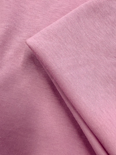 Close-up of Super Cheap Fabrics' Cotton Jersey in Pink Lavender (155cm), featuring a soft fold and smooth, slightly textured lightweight surface.