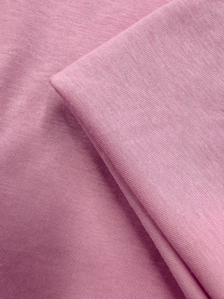 Close-up of Super Cheap Fabrics' Cotton Jersey in Pink Lavender (155cm), featuring a soft fold and smooth, slightly textured lightweight surface.