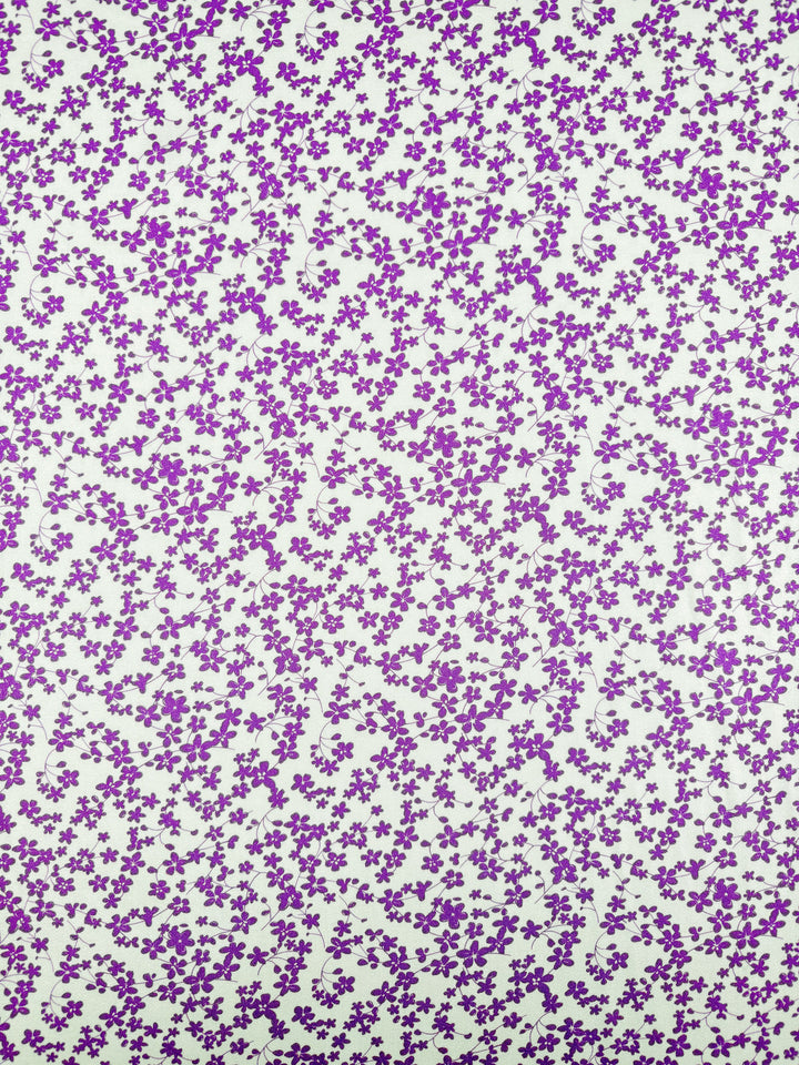 The Mercerised Rayon - Violet Meadow (150cm) by Super Cheap Fabrics features a dense pattern of small purple flowers with green stems on a white background, printed on lightweight rayon fabric.