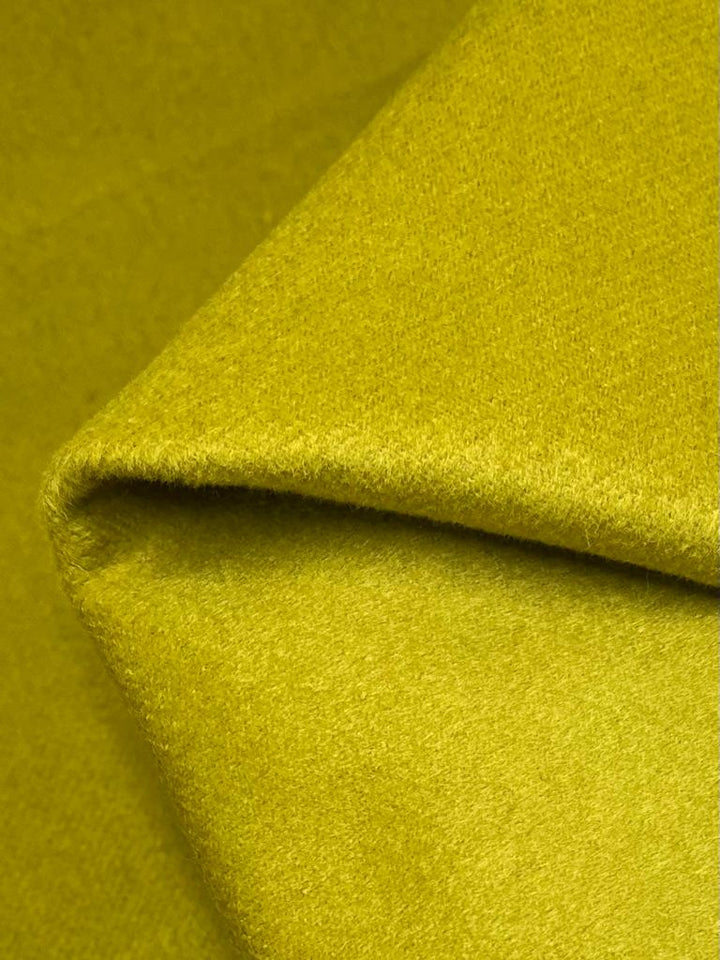 A close-up image of folded Wool Cashmere in the vibrant Golden Palm color. The texture of this fabric appears soft and slightly fuzzy, with a smooth surface that catches the light, giving it a subtle sheen. Perfect for autumn and winter garments, this 150cm fabric from Super Cheap Fabrics is neatly draped to show its thickness and quality.