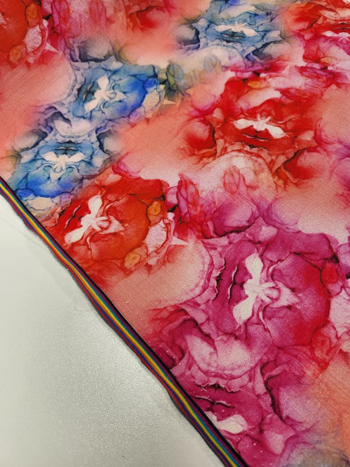 A close-up of the Designer Cotton - Roses by Super Cheap Fabrics shows vibrant, colorful abstract floral patterns in shades of red, pink, and blue. It features a rainbow striping detail along one edge, making it perfect for luxury sewing projects.