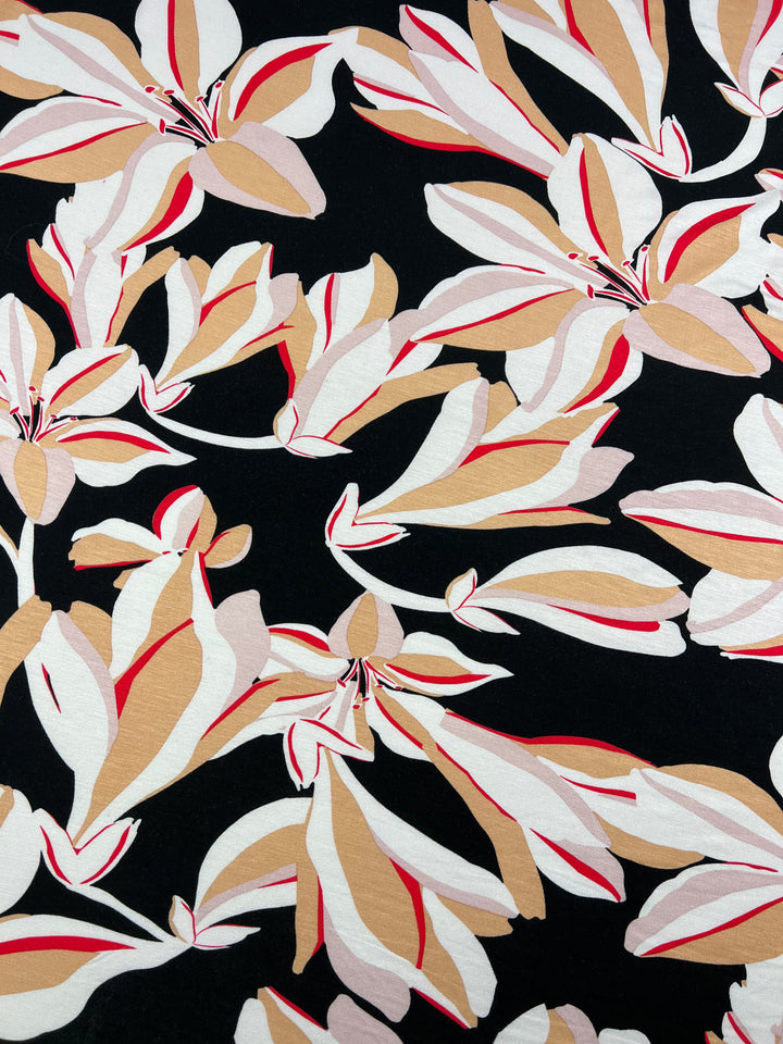 A light-medium weight fabric pattern featuring stylized leaf designs in shades of white, beige, tan, and red against a black background. The flowing lines and varying sizes of the leaves create a harmonious and dynamic composition, perfect for multi-use clothing. This is the Printed Rayon Lycra - Lily - 150cm by Super Cheap Fabrics.