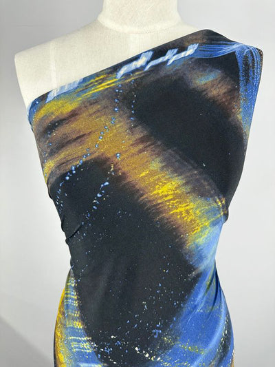 A mannequin showcases a form-fitting, one-shoulder dress crafted from Super Cheap Fabrics' Printed Lycra - Astro - 150cm. The vibrant abstract design boasts dynamic swirls and streaks in shades of blue, yellow, and black, creating a visually striking effect. This medium-weight fabric offers both comfort and durability.