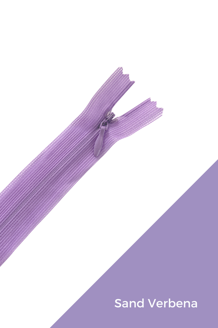 Image of an Invisible Zip - 30cm in a sand verbena color, half-open and placed diagonally across the image. The lower right corner features a diagonal solid block of the same purple shade with the label "Sand Verbena" written in white text. This elegant finish by Super Cheap Fabrics showcases both style and durability.